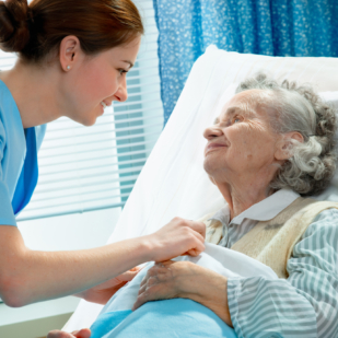 Nurse cares for a elderly woman lying in bed