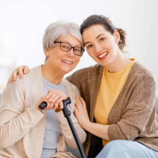 Happy patient and caregiver spending time together. Senior woman holding cane.